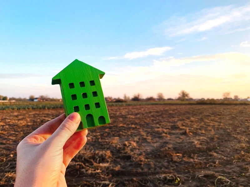 A miniature house on the background of an empty piece of land.